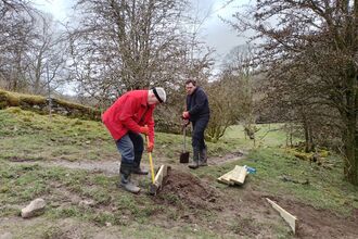 Two volunteers working to repair steps at a nature reserve