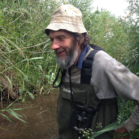 A man in waders in a pond.