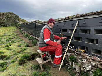 Howard with a hammer working on a wall