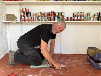 Howard working on his hands and kness in a food pantry