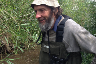 A man in waders in a pond.