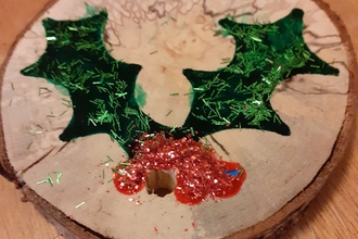 slice of wood with holly leaves and berries painted on