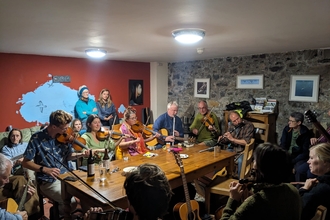 A group of musicians playing music in the hostel lounge. It is crowded and all are playing.