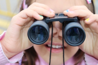 young girl looking through binoculars