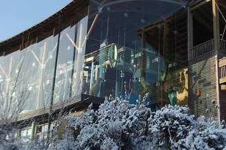 Glass Visitor centre building with snow covered shrubs in foreground