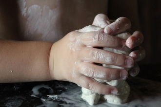child's hands squeezing clay