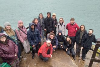 A group of young people on the steps. They are wearing waterproofs and all looking at the camera.