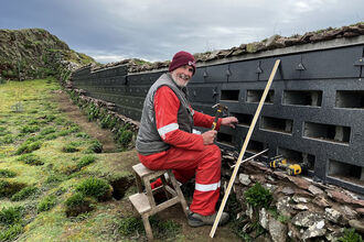 Howard with a hammer working on a wall