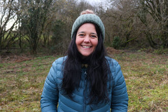 Ceri smiling in a coat and hat outside.