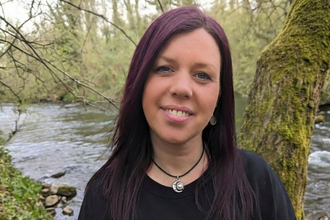 Michelle stood smiling next to a river. 