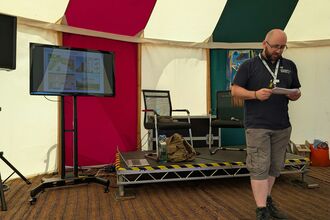 A man stood giving a presentation in a colourful marquee