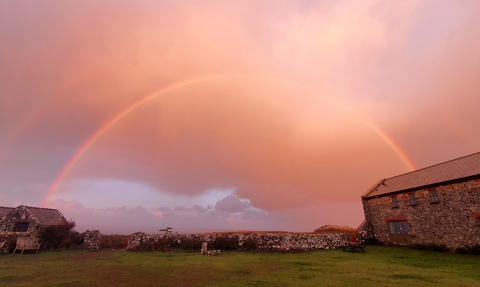 Rainbow in a pink sky. Hostel building can be seen below.