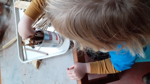 Child putting hollow sticks into a can