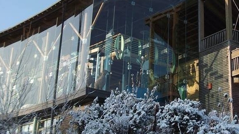 Glass Visitor centre building with snow covered shrubs in foreground