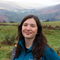 Alice, our Assistant Conservation Officer, standing in field with mountains behind her. 