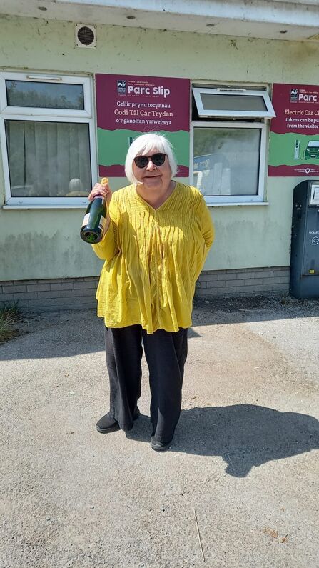 A woman stood holding a bottle of champagne