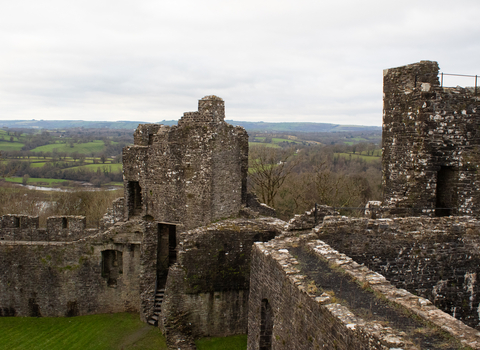 Castle ruins with tree tops and hills in the background. 