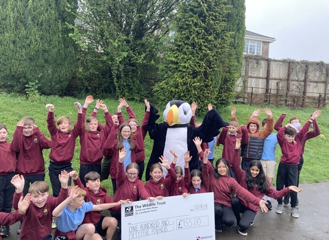 Children holding a giant cheque with our puffin mascot. 