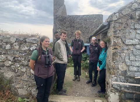 A group of volunteers stand outside the workshop. They look happy.