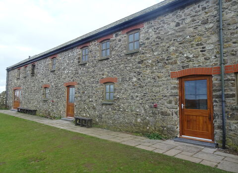 An exterior shot of the Skomer hostel. There are three doors set into the stone wall.